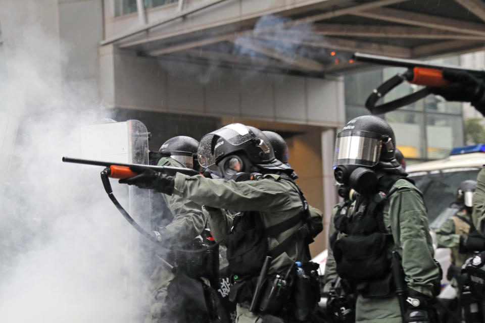 Riot policemen fire weapons during a confrontation with demonstrators during a protest in Hong Kong, Sunday, Aug. 25, 2019. Hong Kong police have rolled out water cannon trucks for the first time in this summer's pro-democracy protests. The two trucks moved forward with riot officers Sunday evening as they pushed protesters back along a street in the outlying Tsuen Wan district. (AP Photo/Kin Cheung)