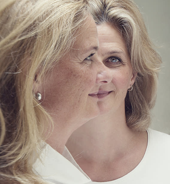 Two women with shoulder-length hair facing different directions. One looks left while the other faces forward. Both wear earrings and white tops