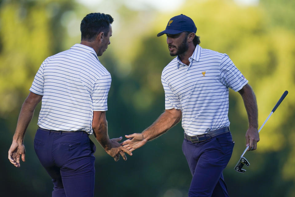 Billy Horschel and Max Homa speak on the 17th green during their fourball match at the Presidents Cup golf tournament at the Quail Hollow Club, Friday, Sept. 23, 2022, in Charlotte, N.C. (AP Photo/Julio Cortez)