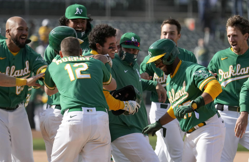 Oakland Athletics' Ramon Laureano, center, celebrates with teammates after two runs scored on a throwing error by Minnesota Twins third baseman Luis Arraez during the 10th inning of a baseball game Wednesday, April 21, 2021, in Oakland, Calif. Laureano safe at first. Oakland won 13-12. (AP Photo/Tony Avelar)