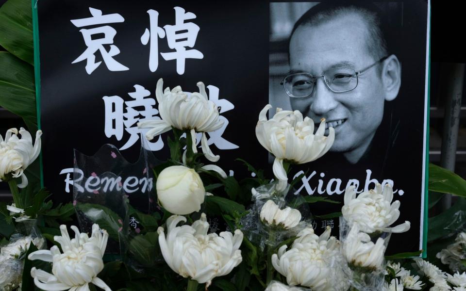 A portrait of late Chinese Nobel Peace laureate Liu Xiaobo is displayed outside the Chinese liaison office in Hong Kong - Credit: (AP Photo/Vincent Yu)