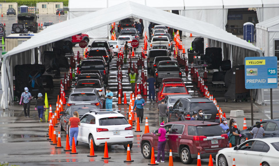 Vehicles line up as healthcare workers help to check-in as citizens is being tested at the COVID-19 drive-thru testing center at Hard Rock Stadium in Miami Gardens on Sunday, Nov. 22, 2020. (David Santiago/Miami Herald via AP)