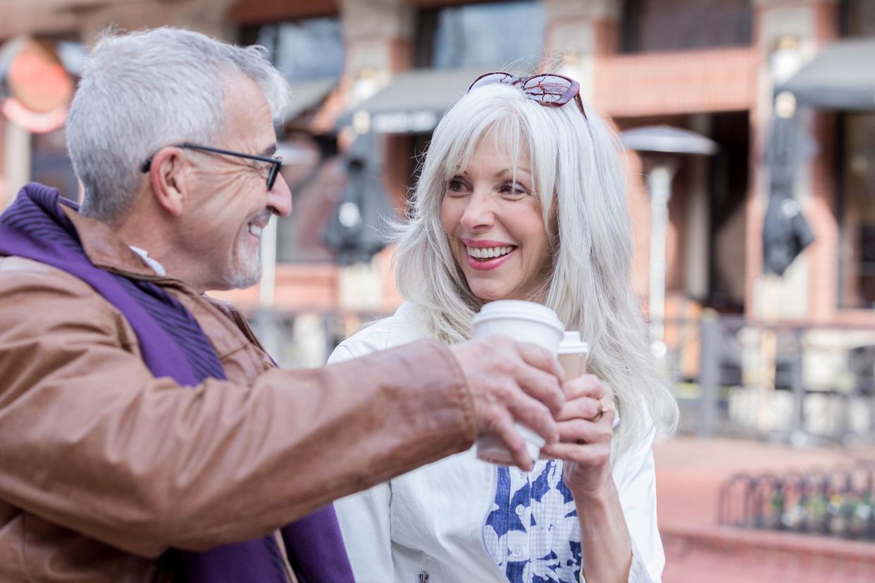 senior couple toast coffee cups while enjoying coffee outdoors, Colorado