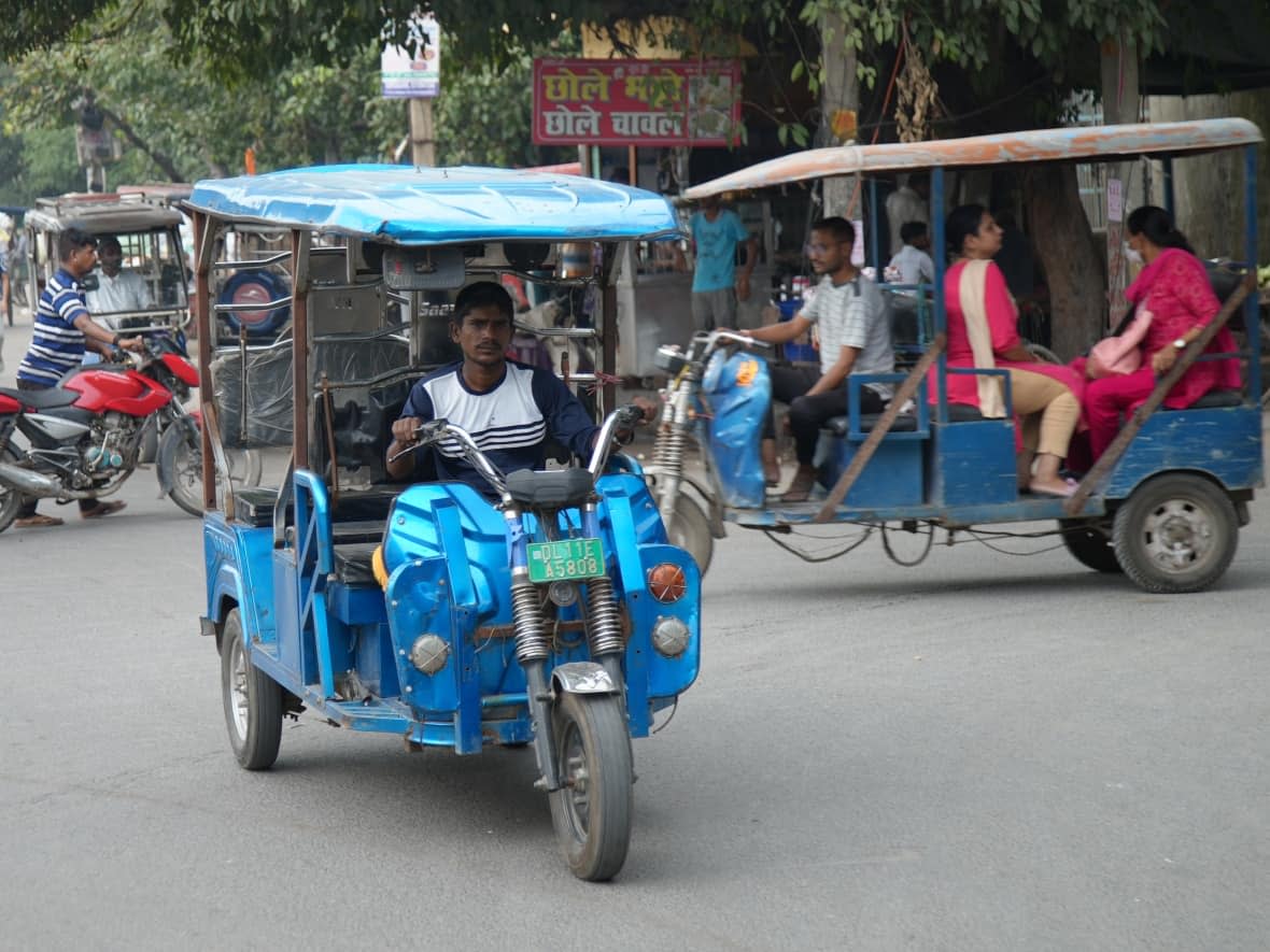 Electric rickshaws are a constant on the streets of New Delhi, often fighting for space outside busy areas as they wait for passengers.  (Salimah Shivji/CBC - image credit)