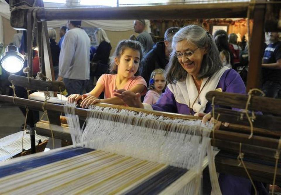 Fiber artist Anne Allison, right, shows Samira Libbus, 8, how to weave on a loom from 1757 in Village of Yesteryear at the North Carolina State Fair in Raleigh, N.C. on Sunday, October 20, 2013. Allison is a heritage craftsperson who says her primary goal at the village is to demonstrate and educate her craft.