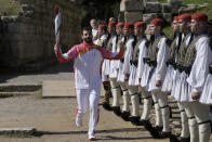 The first torch bearer Greek alpine ski racer Ioannis Antoniou runs past Greek Presidential Guard soldiers during the lighting of the Olympic flame at Ancient Olympia site, birthplace of the ancient Olympics in southwestern Greece, Monday, Oct. 18, 2021. The flame will be transported by torch relay to Beijing, China, which will host the Feb. 4-20, 2022 Winter Olympics. (AP Photo/Petros Giannakouris)