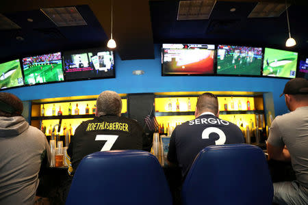 FILE PHOTO - Gamblers watch sports on televisions at Monmouth Park Sports Book by William Hill, shortly after the opening of the first day of legal betting on sports in Oceanport, New Jersey, U.S., June 14, 2018. REUTERS/Mike Segar/File Photo