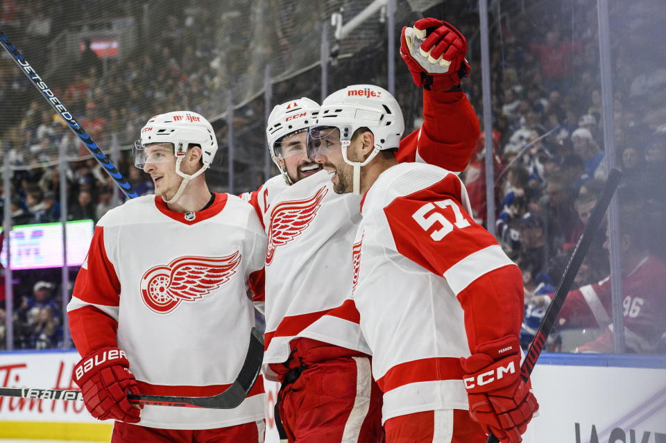 Detroit Red Wings center Dylan Larkin (71) celebrates with left wings Dominik Kubalik (81) and David Perron (57) after scoring against Toronto Maple Leafs goaltender Ilya Samsonov (35) during third-period NHL hockey game action in Toronto, Ontario, Sunday, April 2, 2023. (Christopher Katsarov/The Canadian Press via AP)