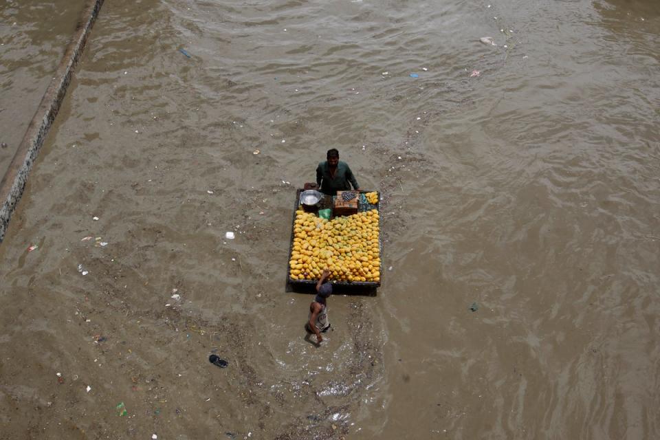 A fruit seller navigates a flooded road after heavy rainfall in Karachi, Pakistan (AP)