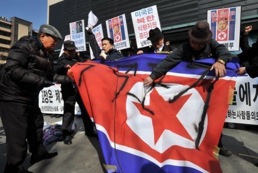 South Korean activists are seen cutting a North Korean national flag during a rally denouncing the North's announcement of a planned satellite launch, in Seoul, on March 20