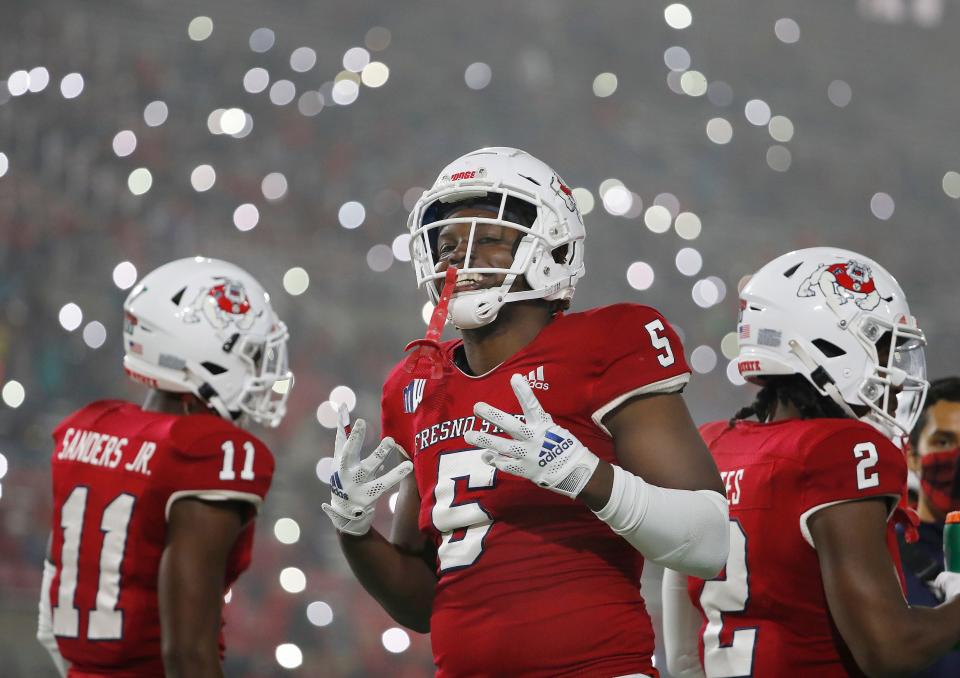 Fresno State defensive end Devo Bridges signals the fourth quarter in the team's NCAA college football game in Fresno, Calif., Saturday, Nov. 13, 2021, as fans turn on the lights on their phones.  (AP Photo/Gary Kazanjian)