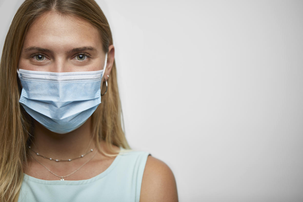 Closeup portrait of a young woman with face mask on the studio against white background.