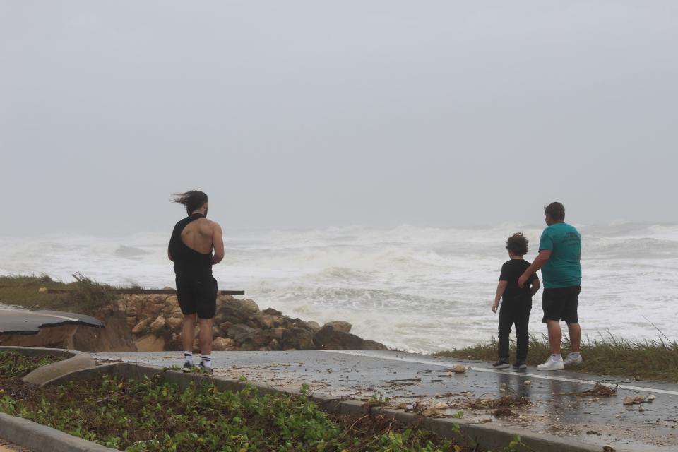 People check out one of the chunks of A1A in Flagler Beach torn off Thursday  by waves driven by  Tropical Storm Nicole.