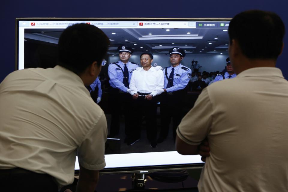 Men look at a picture of disgraced Chinese politician Bo standing trial on the website of a court's microblog, in Jinan