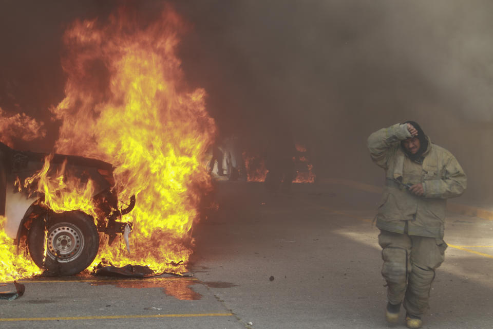 Un vehículo arde luego de ser incendiado por estudiantes de magisterio de una escuela rural que protestaban por la muerte de tiros de un compañero durante una confrontación con la policía el mes pasado, mientras bomberos tratan de sofocar las llamas, en el exterior de la municipalía de Chilpancingo, México, el 8 de abril de 2024. (AP Foto/Alejandrino González)
