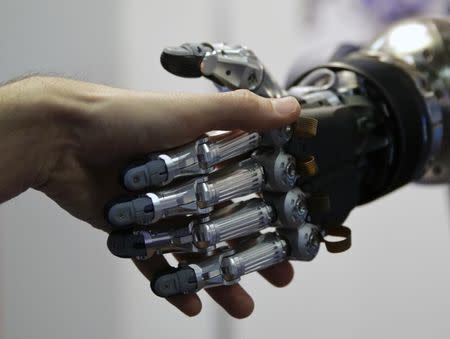 A man shakes hands with a humanoid robot during the International Conference on Humanoid Robots in Madrid November 19, 2014. REUTERS/Andrea Comas