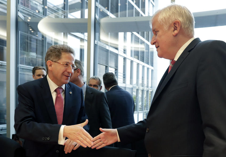 Hans-Georg Maassen, left, head of the German Federal Office for the Protection of the Constitution, and German Interior Minister Horst Seehofer, right, shake hands as they arrive for a hearing at the home affairs committee of the German federal parliament, Bundestag, in Berlin, Germany, Wednesday, Sept. 12, 2018. (AP Photo/Michael Sohn)