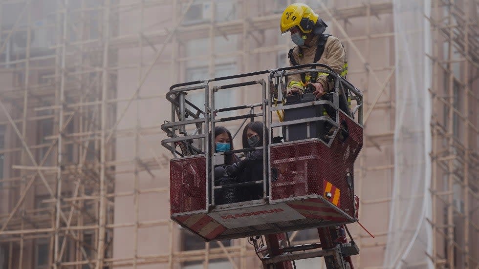 Two women are rescued by a firefighter in a bucket crane outside the World Trade Centre in Hong Kong