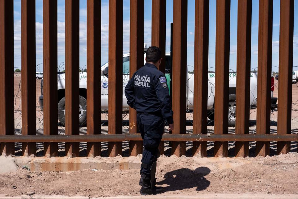 A Border patrol unit (behind the fence) and a Mexico's federal police guard near the US-Mexico border fence as US President Donald Trump visits Calexico, California, as seen from Mexicali, Baja California state, Mexico, on April 5, 2019. - President Donald Trump flew Friday to visit newly built fencing on the Mexican border, even as he retreated from a threat to shut the frontier over what he says is an out-of-control influx of migrants and drugs. (Photo by Guillermo Arias / AFP)        (Photo credit should read GUILLERMO ARIAS/AFP via Getty Images)