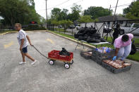 Lottie Gray, left, pulls her cart after receiving a bag of food from Houston Independent School District food distribution site Monday, April 6, 2020, in Houston. HISD relaunched their food distribution efforts throughout the district Monday, with a streamlined process that will implement increased safety measures. (AP Photo/David J. Phillip)