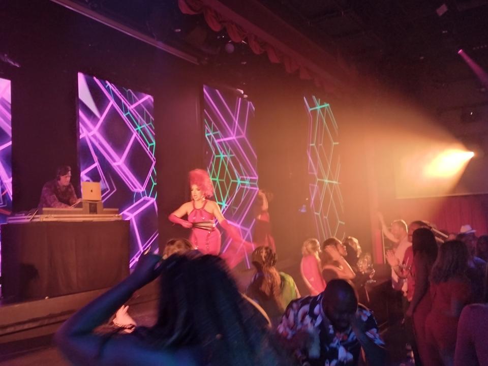 A performer leading a show with a DJ on stage in front of an audience.
