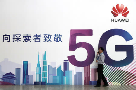 FILE PHOTO: A man talks on his mobile phone beside Huawei's billboard featuring 5G technology at the PT Expo in Beijing, China, September 26, 2018. REUTERS/Stringer/File Photo