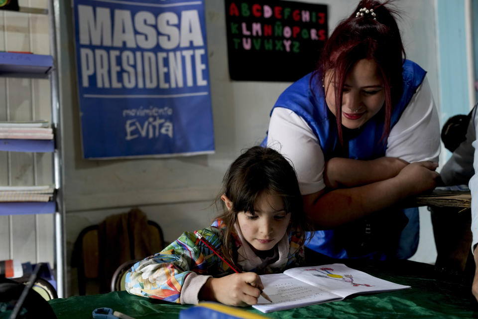 A student gets help with her schoolwork in a space run by the Evita Movement, a Peronist social organization, in Cuidad Evita on the outskirts of Buenos Aires, Argentina, Monday, Nov. 13, 2023. As Argentina heads for a presidential Nov. 19 runoff election, the decades-old populist movement known as Peronism has Economy Minister Sergio Massa, the ruling party's presidential candidate, working overtime to keep once-steadfast supporters from straying to his opponent, right-wing populist Javier Milei. (AP Photo/Natacha Pisarenko)