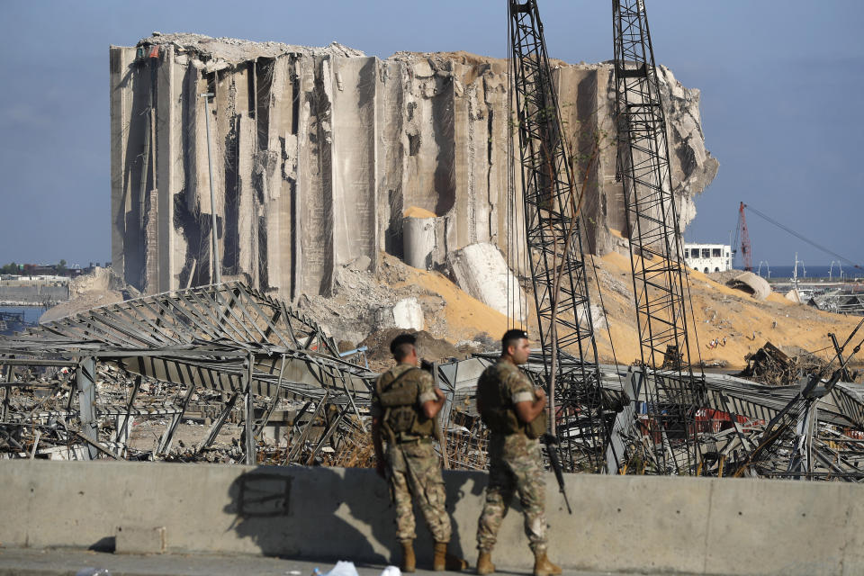 Lebanese army soldiers stand guard at the scene where an explosion hit on Tuesday the seaport of Beirut, Lebanon, Thursday, Aug. 6, 2020. Lebanese army bulldozers plowed through wreckage to reopen roads around Beirut's demolished port on Thursday as the government pledged to investigate the devastating explosion and placed port officials under house arrest. (AP Photo/Hussein Malla)