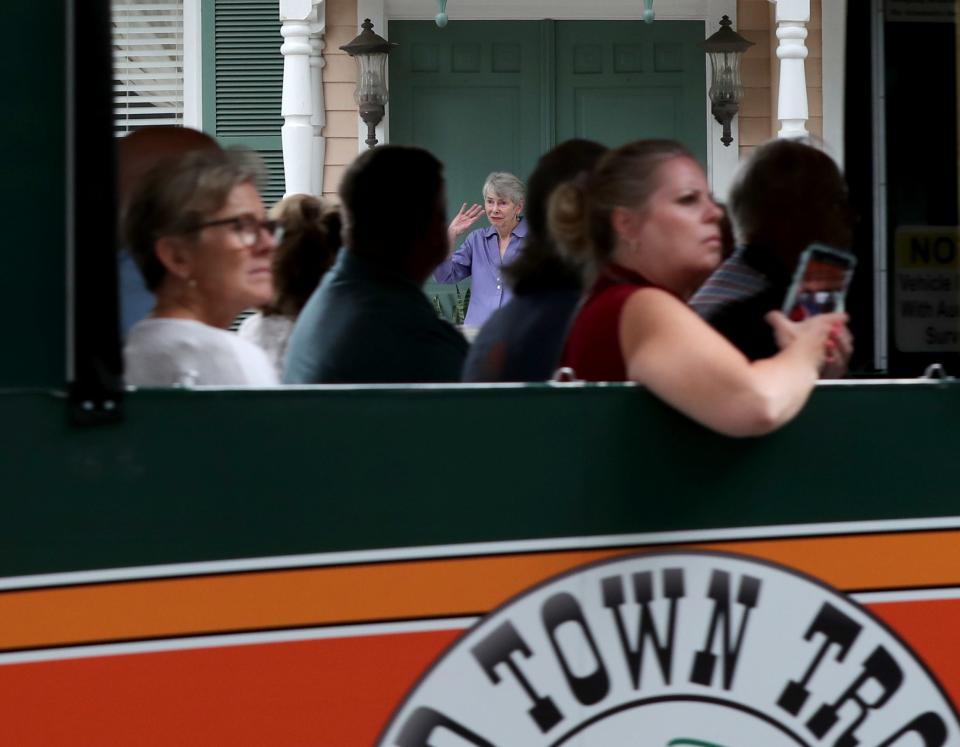 Susan Prutzman stands on the porch of her home off Warren Square as one of the many Trollies that pass each day drives by her home.