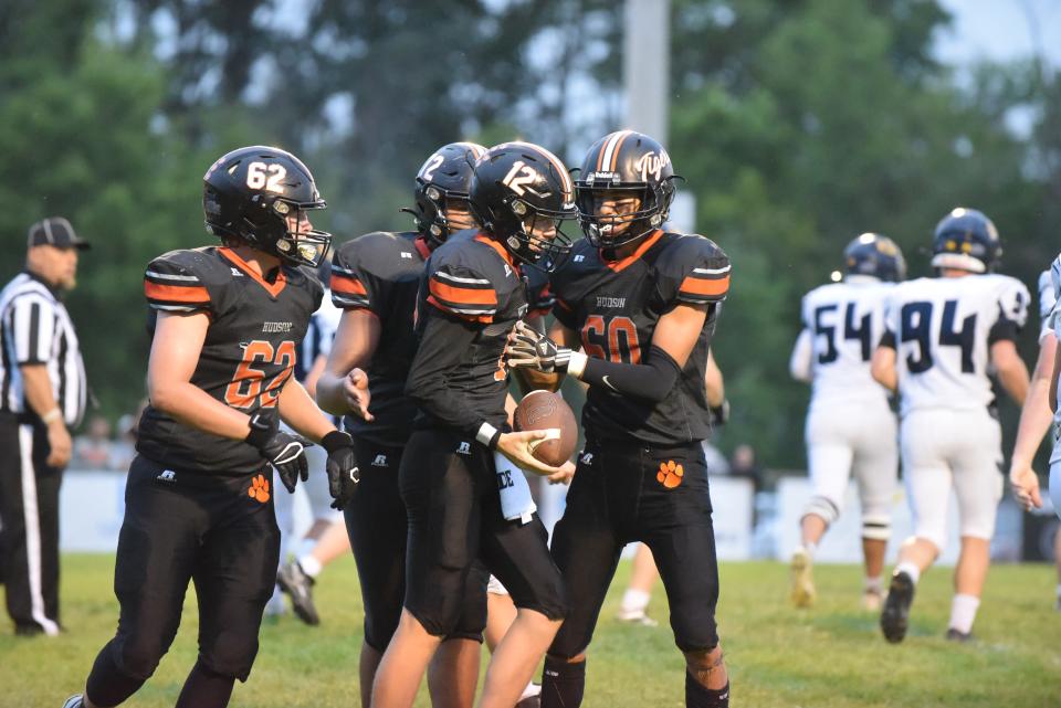 Hudson's KJ Walker (12) celebrates a 2-point conversion with Bradley Bertram (62), Angelo Moreno (60) and Malachi Marshall (back) during Friday's game against Hillsdale.