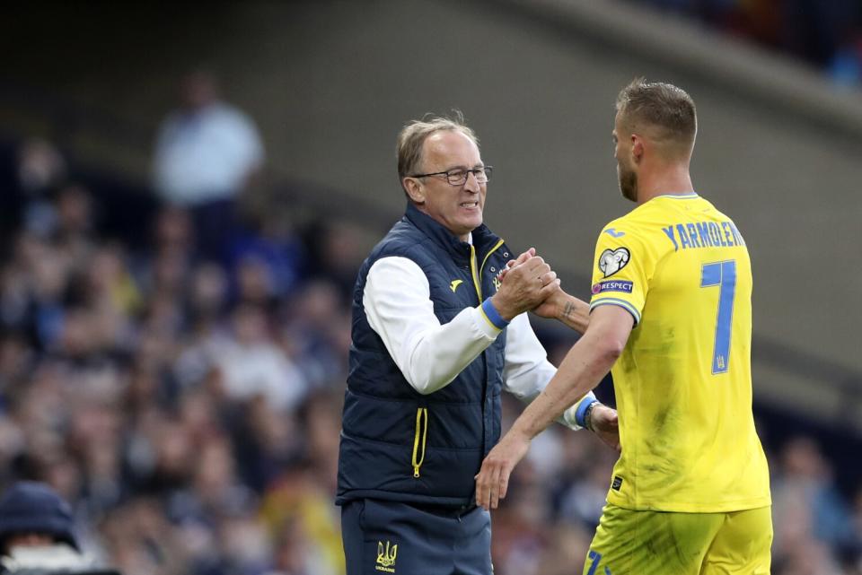 Ukraine coach Olexandr Petrakov, left, shakes hands with Andriy Yarmolenko