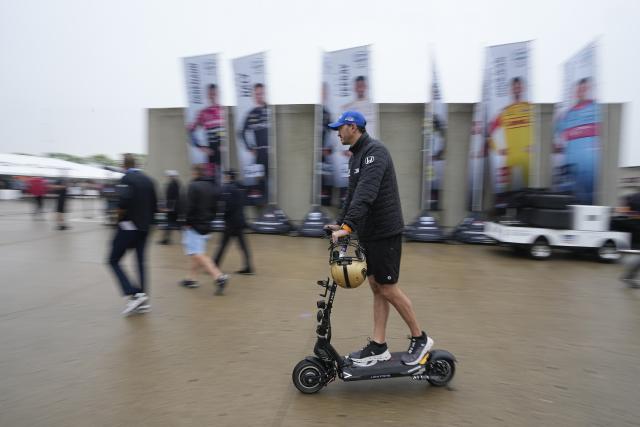 Graham Rahal rides his scooter through the garage area during a rain delay before practice for the Indianapolis 500 auto race at Indianapolis Motor Speedway, Tuesday, May 16, 2023, in Indianapolis. (AP Photo/Darron Cummings)