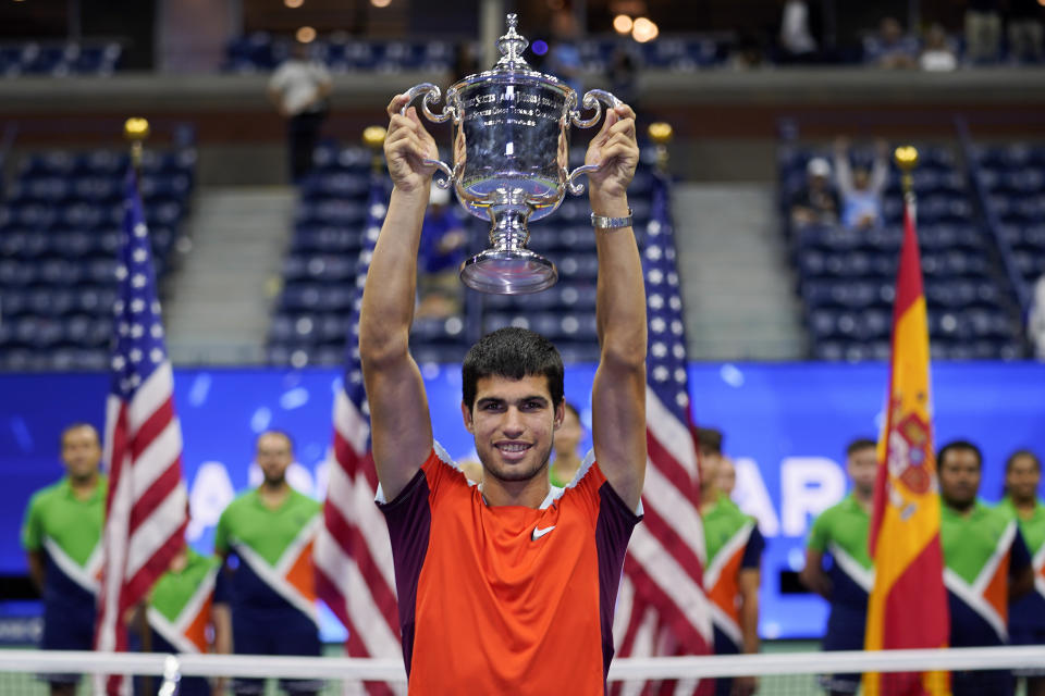 Carlos Alcaraz alza el trofeo de campeón de US Open tras derrotar a Casper Rued en la fina, el domingo 11 de septiembre de 2022. (AP Foto/Charles Krupa)