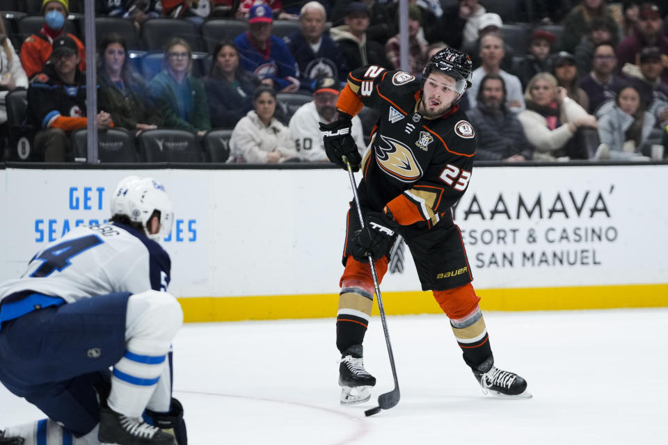 Anaheim Ducks center Mason McTavish, right, takes a shot as Winnipeg Jets defenseman Dylan Samberg watches during the first period of an NHL hockey game Friday, Jan. 5, 2024, in Anaheim, Calif. (AP Photo/Ryan Sun)