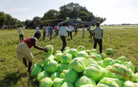 People unload relief food material from an Indian Air Force helicopter to be distributed among the flood victims, on the outskirts of Allahabad, India, August 24, 2016. REUTERS/Jitendra Prakash
