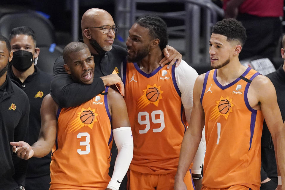 Phoenix Suns head coach Monty Williams, second from left, hugs Chris Paul, left, and Jae Crowder, second from right, as Devin Booker stands by as time runs out in Game 6 of the NBA basketball Western Conference Finals against the Los Angeles Clippers Wednesday, June 30, 2021, in Los Angeles. The Suns won the game 130-103 to take the series 4-2. (AP Photo/Mark J. Terrill)