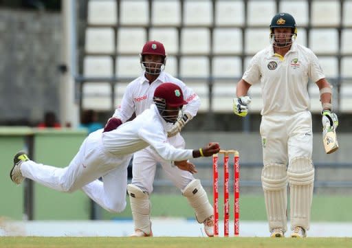 West Indies player Kraigg Brathwaite makes a flying catch to dismiss Australian batsman Ben Hilfenhaus (R) as Carlton Baugh looks on during the fourth day of the third test match between the West Indies and Australia in Roseau, Dominica