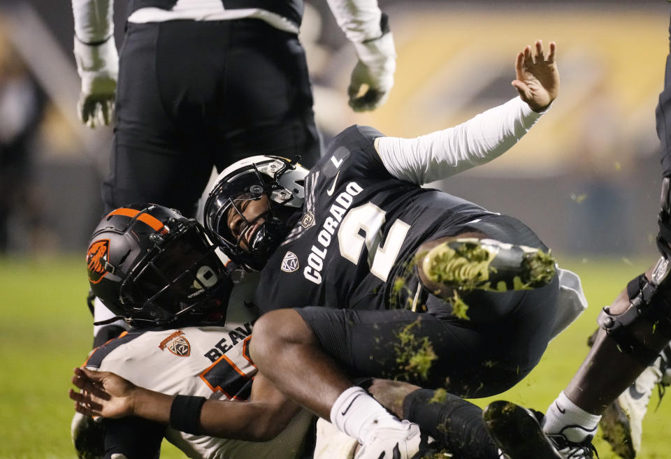 FILE - Oregon State linebacker Andrew Chatfield Jr., left, pulls down Colorado quarterback Shedeur Sanders in the second half of an NCAA college football game in this file photograph taken Saturday, Nov. 4, 2023, in Boulder, Colo. Deion Sanders is accomplishing what he pledged to do by overhauling his offensive line to better protect his often-hit quarterback son. The Colorado coach reached into the transfer portal and brought in linemen from the University of Houston, Connecticut, Indiana and UTEP. (AP Photo/David Zalubowski, File)