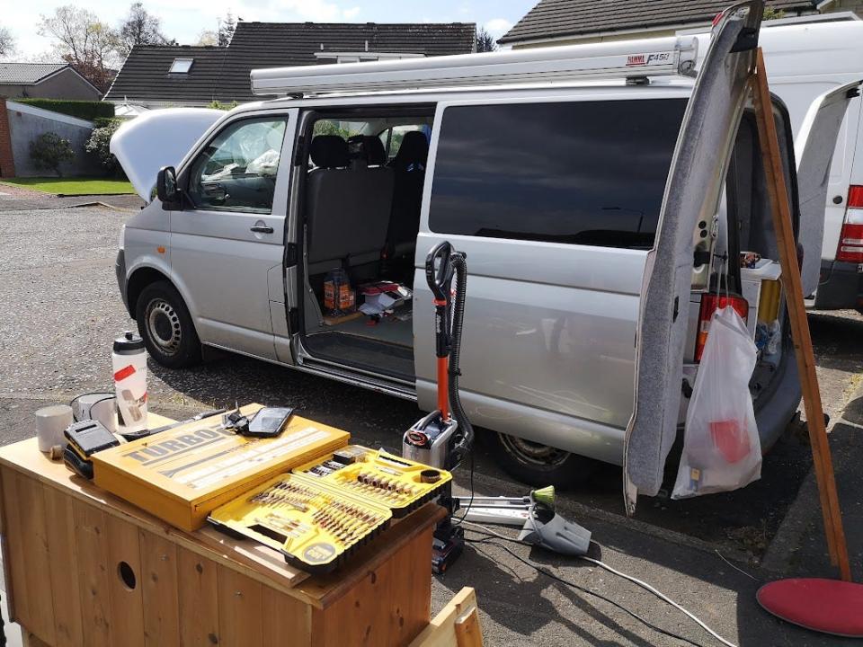a silver van with tools in front of it and an open door