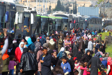 People that were evacuated from the two villages of Kefraya and al-Foua walk near buses, after a stall in an agreement between rebels and Syria's army, at insurgent-held al-Rashideen, Aleppo province, Syria April 15, 2017. REUTERS/Ammar Abdullah