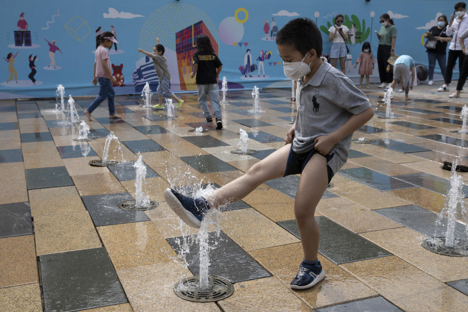 A child wearing a mask to curb the spread of the coronavirus plays with a water fountain on Children's Day in Beijing on Monday, June 1, 2020. (AP Photo/Ng Han Guan)