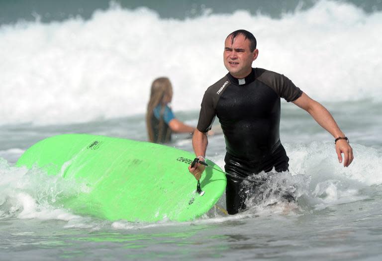 French Catholic priest Rene-Sebastien Fournie surfs at a beach in Bidart, southwestern France, on September 3, 2013