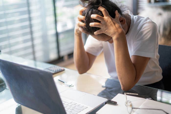 a woman holding her head sitting at a desk looking stressed