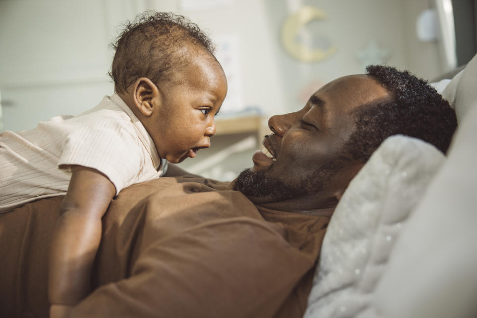 Young father spending time with baby son. He is holding his cute little baby boy in arms at home.