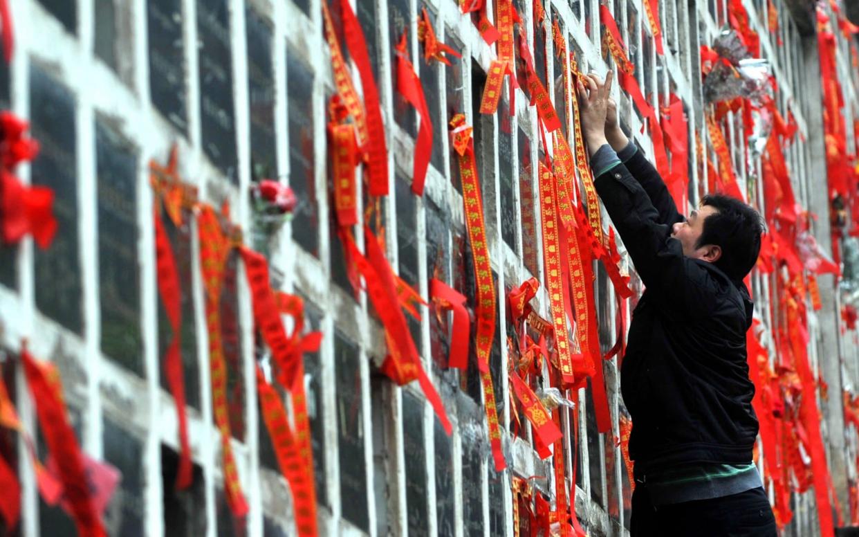 A man cleans a niche of a columbarium as people across China pay their respects to deceased friends and relatives  - Getty Images AsiaPac 