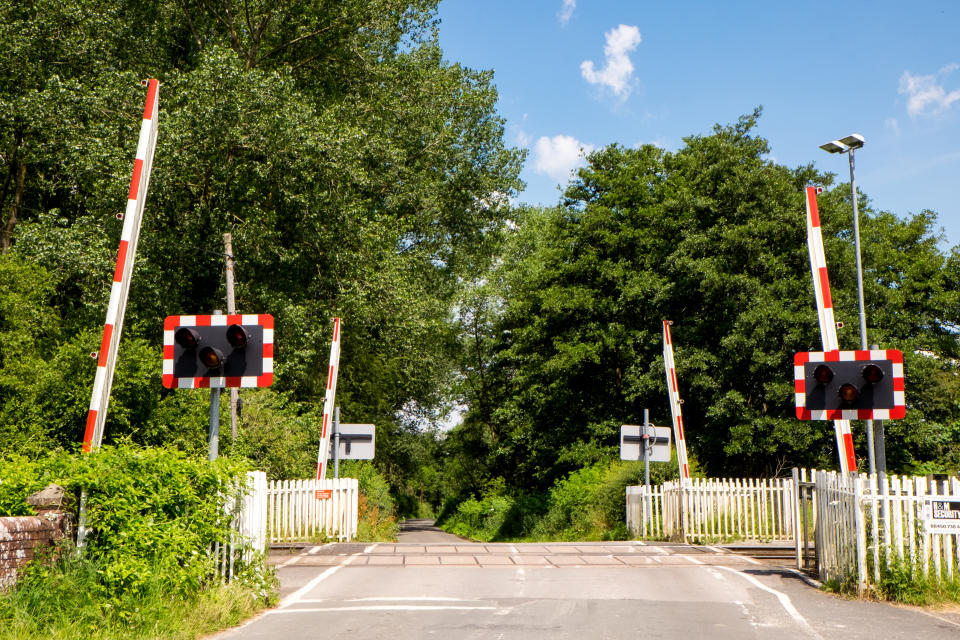 Country road with a railroad level crossing with the gates raised.