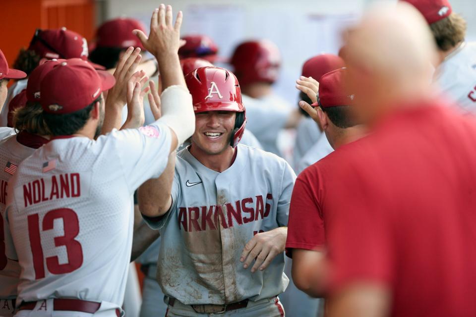 Arkansas players celebrate with infielder Chris Lanzilli (18) after he scored a run during an NCAA college baseball tournament regional game against Oklahoma State in Stillwater, Oklahome, on Monday, June 6, 2022.