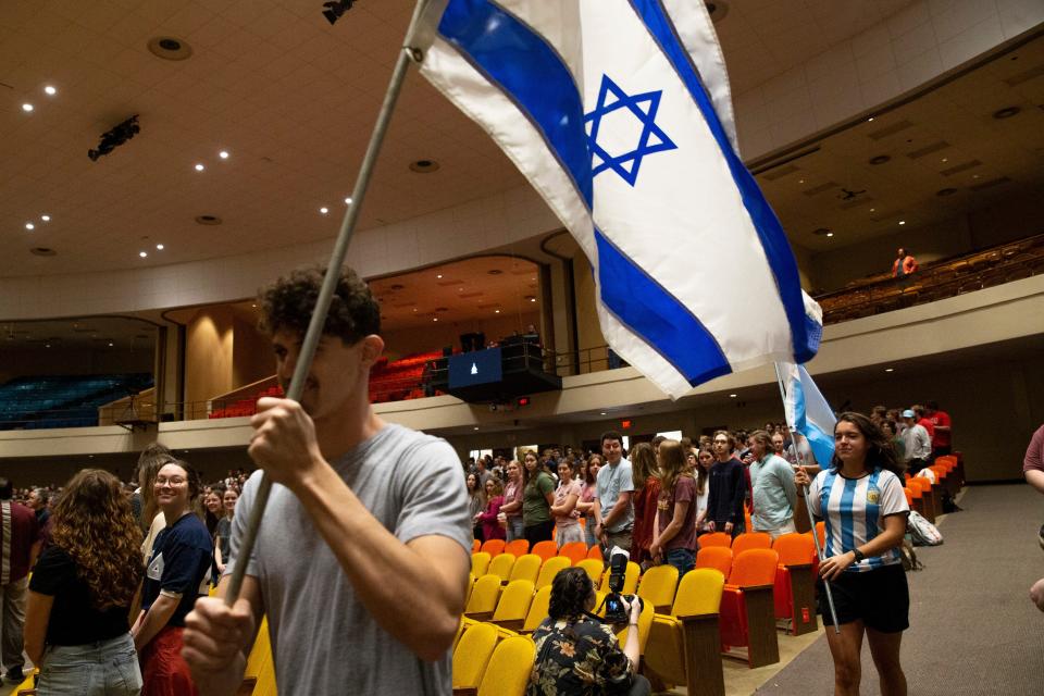 Omer Shifris, who is from a place 30 minutes outside Tel Aviv in Israel, walks to the stage carrying the Israeli flag with Delfina Molina following behind him with the Argentinian flag during International Student Day at Freed-Hardeman University in Henderson, Tenn., in February. "It felt good," Shifris said on speaking about Israel. "I'm the only one for Israel so to be the face of Israel here and share my values and culture with everyone."