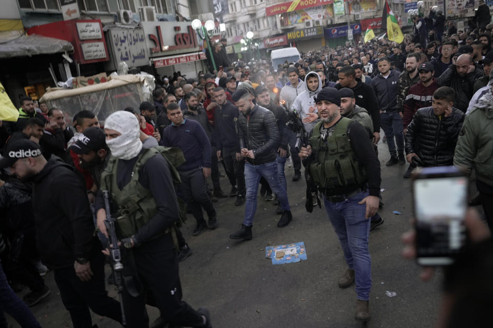 A Palestinian gunman shoots in the air during the funeral procession of three Palestinian militants who were killed by Israeli forces, in the occupied West Bank city of Nablus, Tuesday, Feb. 8, 2022. Israel said it killed three Palestinian militants in Nablus who had been responsible for recent shooting attacks. (AP Photo/Majdi Mohammed)