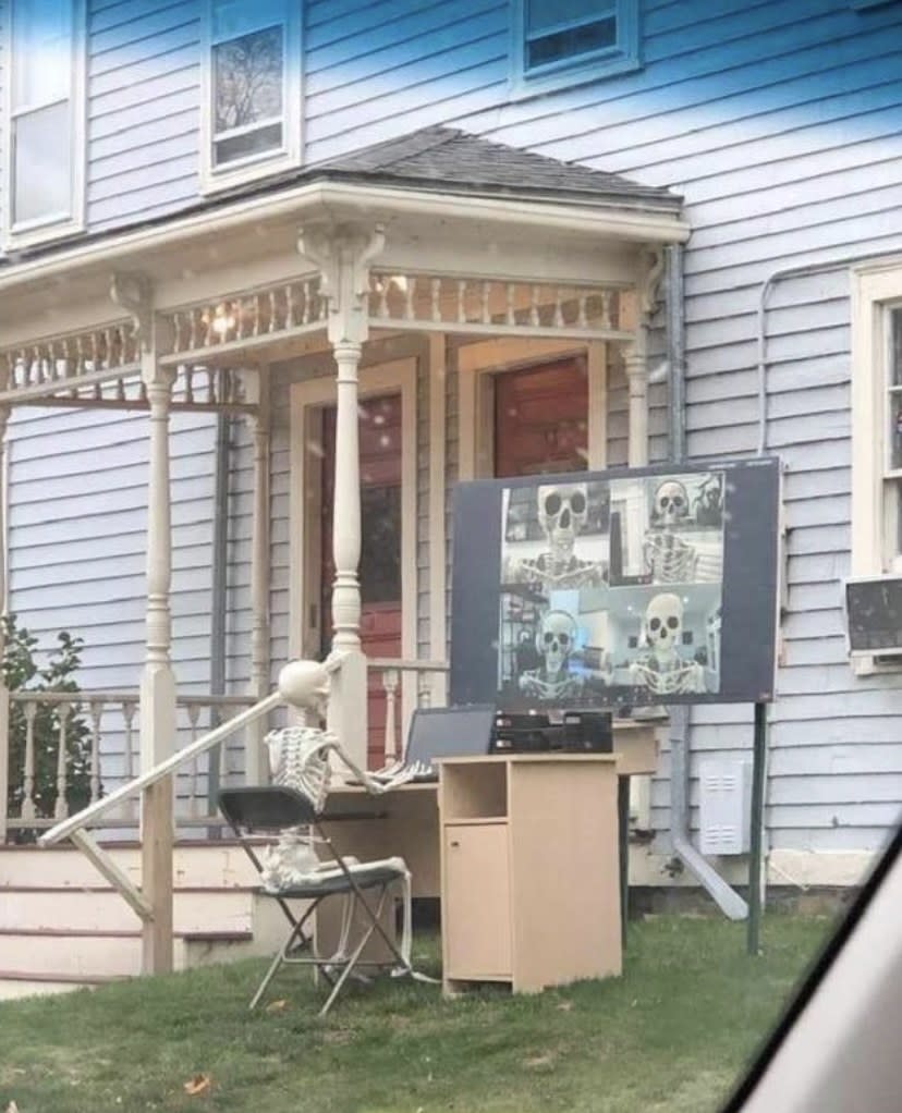 skeleton sitting at a desk with a projection screen of a zoom call